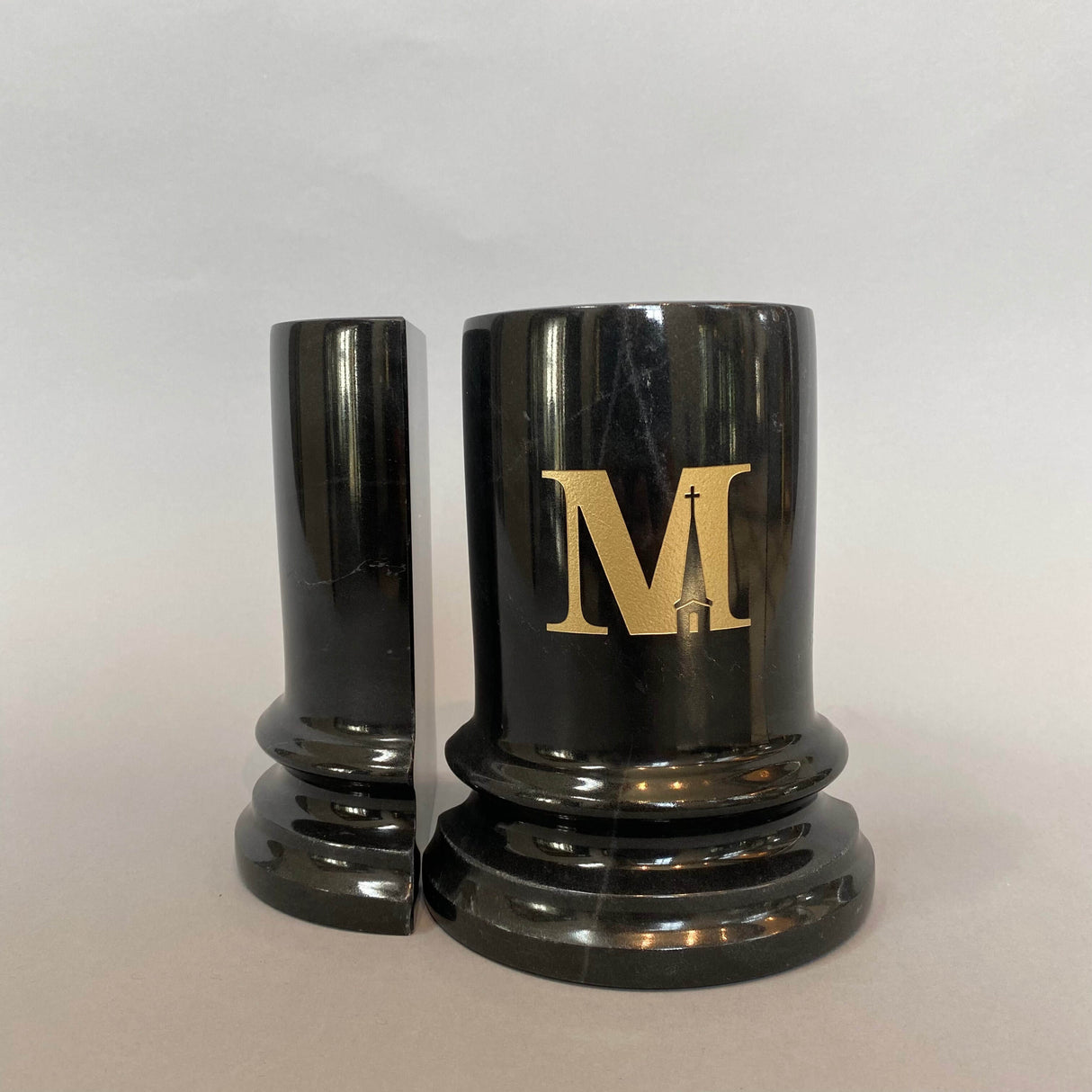 A pair of heavy marble bookends with a gold Midwestern M on one.