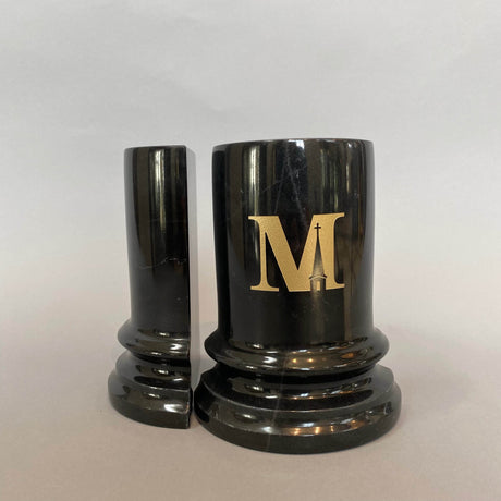 A pair of heavy marble bookends with a gold Midwestern M on one.